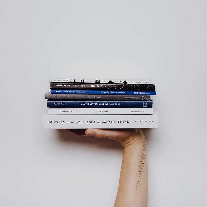 a hand holding a stack of printed books