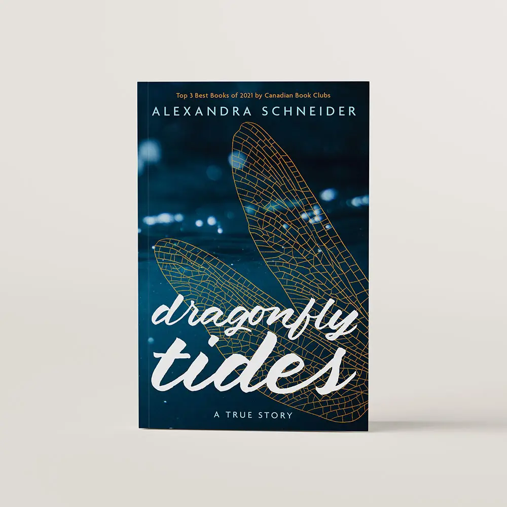 Book cover for Dragonfly Tides by Alexandra Schneider. The cover shows a close up shot of the surface of the ocean with an outline of dragonfly wings overlaid on the image.