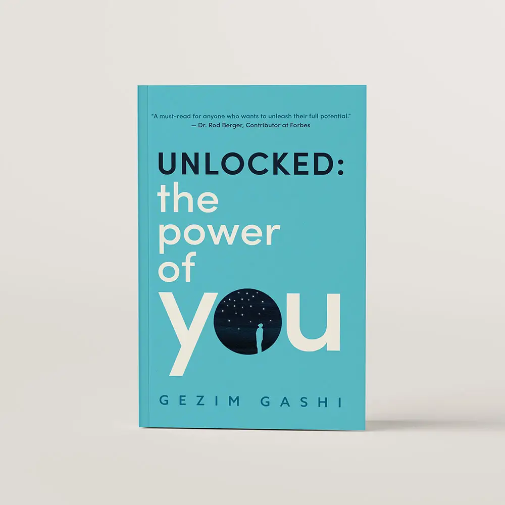 Book cover design for Unlocked: The Power of You by Gezim Gashi. The cover is bright blue with large cream text. The letter O in the word you is made up of a dark night sky with cut out of a person gazing up in the sky within it.