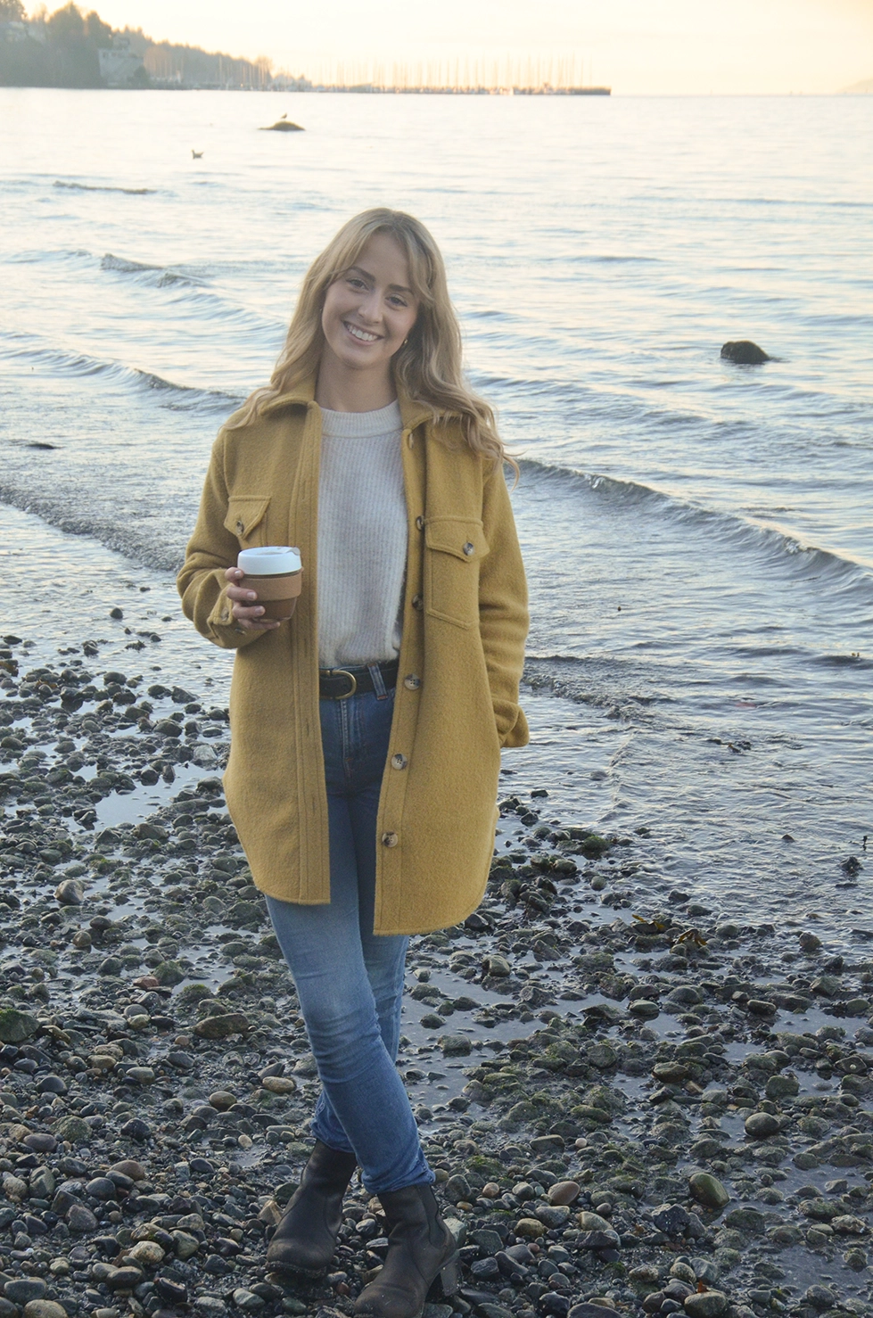 Photo of fleck founder Jazmin Welch in a yellow overcoat with sunshine coming behind her blond hair.