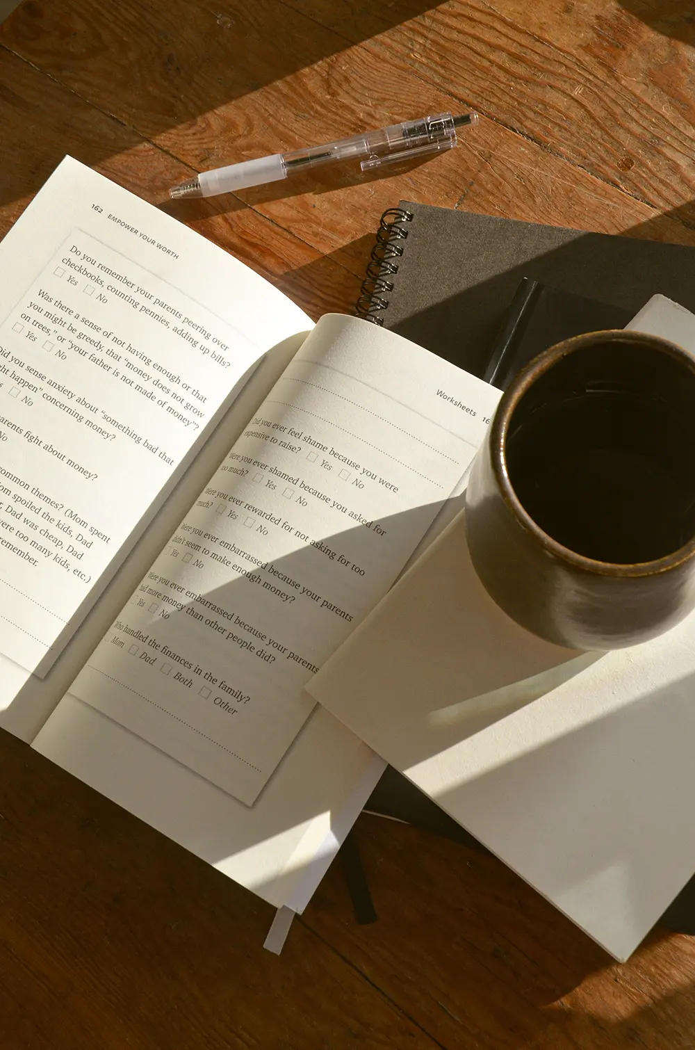 A book design example of an interior workbook design. The book is sitting on a desk with a pen and notebooks and a cup of coffee.